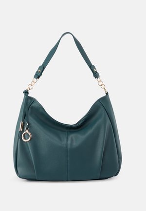 Sac à bandoulière en cuir bleu sarcelle avec des maillons de chaîne dorée sur la sangle et un pendentif rond doré attaché près du coin supérieur gauche.