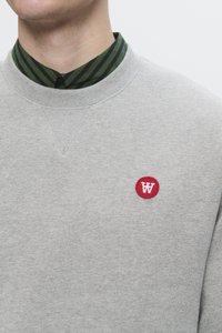 Gray sweatshirt with a round red patch featuring a white letter 'W'. The collar displays green and navy vertical stripes. Soft texture.