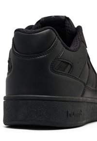 Close-up of the back and side of a black sneaker with textured sole, black stitching, and a padded collar, no visible branding or laces.