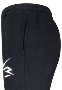 Pantaloni della tuta neri con tasca laterale e logo stilizzato bianco vicino all'anca, mostrati da una vista laterale ravvicinata.