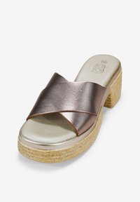 Sandalias de plataforma metálicas color bronce con un diseño de correas cruzadas, suela acolchada y una base de textura tejida de color claro.