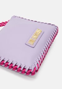 Fialová kožená taška s růžovými pletenými akcenty, se zlatou logovou destičkou. Obdélníkový tvar, hladká textura a tkané detaily podél okrajů.