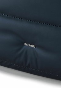 Bolsa acolchada azul marino con textura suave, con el logo plateado "PICARD" y costuras bien hechas. Diseño compacto adecuado para el uso diario.