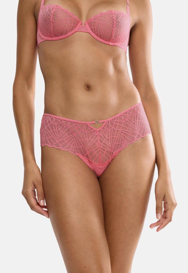 Kvinde iført lyserød blonder-bh og matchende high-waist blonder-trusser med geometrisk mønster, vist fra skuldre til øvre lår.