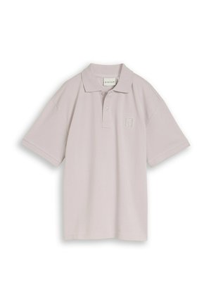 Jasnobeżowa koszulka polo z krótkim rękawem, z dwoma guzikami i logo "BEST" po lewej stronie klatki piersiowej.