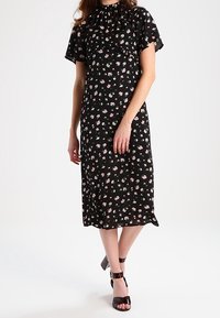 Black floral dress with short flutter sleeves, ruffled neckline, midi length, featuring a pattern of small pink and white flowers.