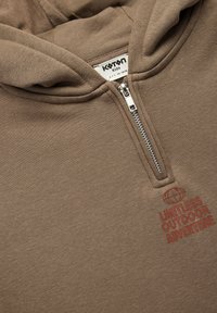 Brązowy sweatshirt z kapturem i zamkiem, z napisem "NIEOGRANICZONE PRZYGODY NA ŚWIERZYM POWIETRZU" w kontrastującym czerwonym kolorze.