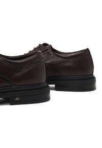 Donkerbruine leren schoenen met een glad oppervlak, ronde neus en zwarte rubberen zool. Bevat subtiele stiksels en een laag profiel ontwerp.