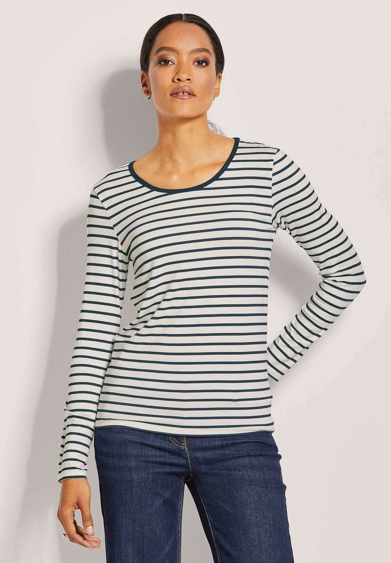 Langärmliges gestreiftes Hemd in Creme mit navyblauen horizontalen Streifen. Rundhalsausschnitt, taillierte Passform und weiche Textur. Kombiniert mit Jeans.