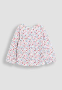 Blusa blanca de manga larga para toddler con pequeño estampado floral en rojo, azul y rosa, con escote redondo y mangas ligeramente fruncidas.