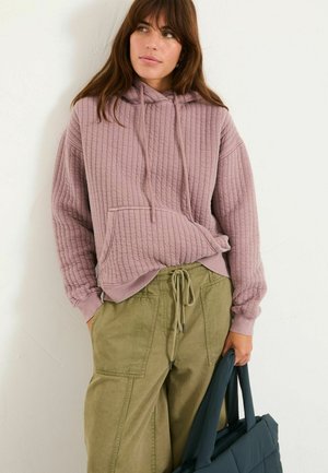 Helle mauve gestepte Kapuzenjacke mit Kordelzug und Fronttasche, kombiniert mit olivgrünen, locker sitzenden Cargo-Hosen.