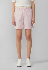 Pantaloni corti rosa chiaro in cotone, con risvolti, tasche laterali e una cintura intrecciata bianca. Abbinati a sneakers bianche.