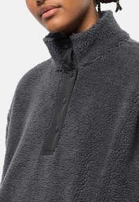 Pullover in pile grigio con colletto alto, dotato di una patta con bottoni a pressione nera e una finitura morbida e testurizzata.