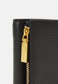 Black leather wallet with a textured finish, featuring a gold zipper and hardware. Accented with a gold logo tag attached to the zipper.