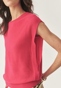 Top a maniche corte rosa, lavorato a maglia, con scollatura e orlo a coste, impreziosito da spacchi laterali per un fit rilassato e una finitura testurizzata.