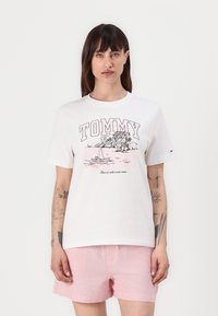 Balta medvilninė marškinėliai trumpomis rankovėmis, su rožine grafika, vaizduojančia palmės ir jachtą, ir tekstu „TOMMY Jeans“.}}