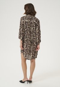 Kimono štýl šaty s leopardím vzorom z ľahkého materiálu, béžový základ s tmavohnedými škvrnami, so bočnými rozparkami a trojštvrťovými rukávmi.
