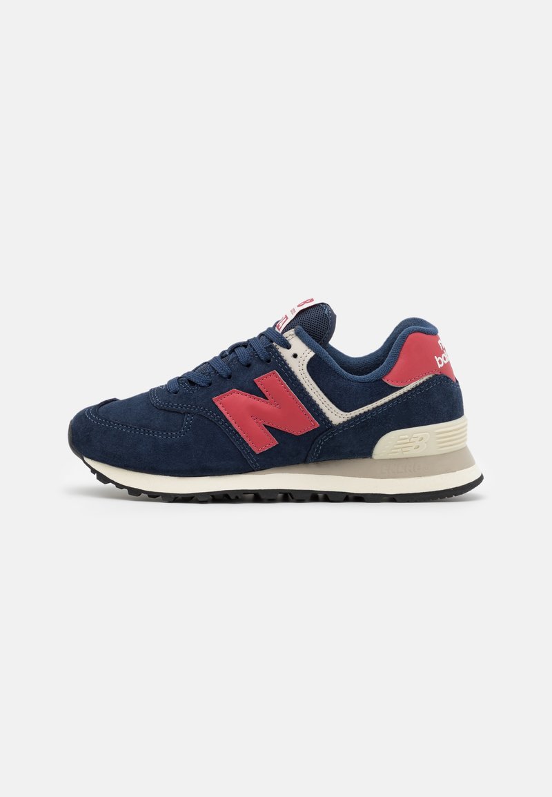 Baskets New Balance bleu marine et rouges avec lacets, semelle intermédiaire crème, semelle extérieure noire texturée et col rembourré, vues de côté sur fond blanc.