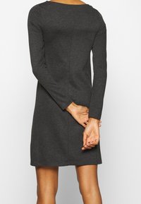 Mörkgrå långärmad klänning i mjukt tyg, med rundad halsringning och avslappnad passform, med synliga sömmar på baksidan.