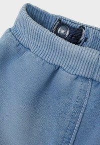 Leggings in cotone azzurro chiaro con vita a coste, dotati di chiusura a bottone e dettagli di cucitura in contrasto lungo le cuciture laterali.