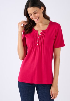 Roze kortemouwen shirt met een ronde hals, voorzien van een knoopsluiting aan de voorkant en geplooide details op het lichaam. Zachte, gladde stof.