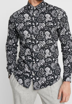 Chemise noire avec un motif paisley blanc, col boutonné et manches longues, fabriquée dans un tissu lisse avec une coupe ajustée.