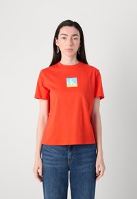 Rode katoenen T-shirt met een ronde halslijn en korte mouwen, featuring een blauw en geel vierkant logo ontwerp op de voorkant. Eenvoudige snit.