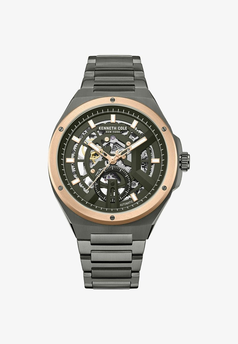 Montre automatique avec un boîtier rond, un cadran vert, un design squelette, des accents dorés et un bracelet en acier inoxydable. Dispose d'index horaires et d'un affichage de la date.