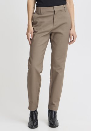 Bukser i brun, skræddersyet design med lige ben, med bæltesløjfer og forlommer, parret med sorte ankelstøvler.