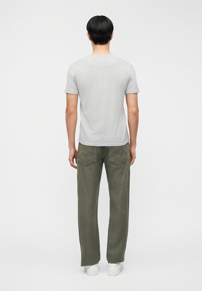 Γκρι κοντομάνικη μπλούζα συνδυασμένη με χακί χαλαρής εφαρμογής παντελόνι. Το ντύσιμο περιλαμβάνει λευκά αθλητικά παπούτσια και έχει απλό, καθαρό σχεδιασμό.