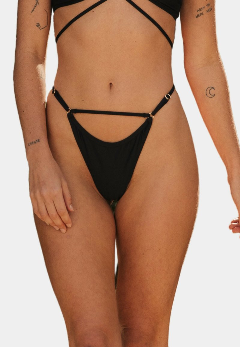 Czarny bikini o minimalnym pokryciu, z cienkimi ramiączkami i złotymi akcentami. Gładka tekstura i okrągły kształt na dole.