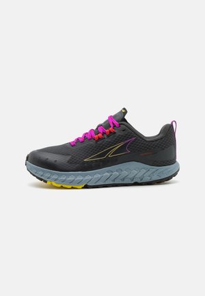 Scarpa da trail running nera e grigia con stringhe rosa, logo giallo, suola spessa e strutturata blu e una linguetta per il trasporto sul tallone.