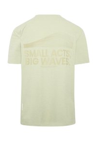 Lys grøn t-skjorte med en stor, beige grafisk tekst på baksiden som leser "SMÅ HANDLINGER, STORE BØLGER" med et bølgedesign over.