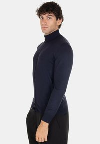 Maglione zip-up blu navy realizzato in tessuto lavorato a maglia, con colletto alto e maniche aderenti, dalla silhouette elegante e dal design minimalista.
