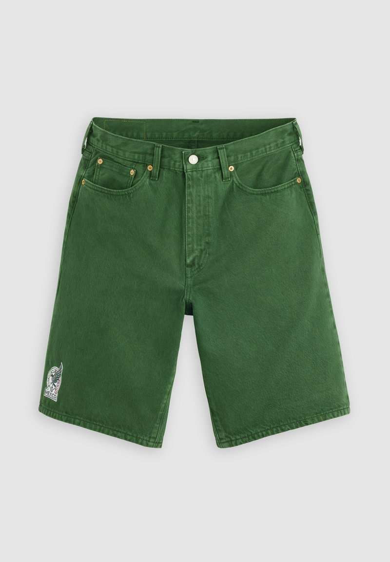 Grüne Denim-Shorts mit Gürtelschlaufen, Frontknopf, Taschen und einem kleinen weiß-schwarzen bestickten Aufnäher auf dem linken Bein.