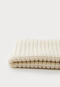 Beige knitted fabric, featuring textured, ribbed design with folded edges. Soft, thick material suggests warmth and comfort.