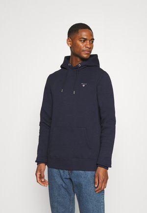 Navyblauwe hoodie gemaakt van zachte stof, met een voorzak, trekkoord en klein logo op de borst. Casual fit.