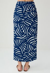 Gonna maxi blu con motivo ondulato bianco. Presenta una vita arricciata e una silhouette dritta. Realizzata in tessuto testurizzato.