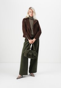Brown suede biker jacket, olive wide-leg pants, green fabric handbag with pockets, and light brown pointed flats. Simple, modern outfit.