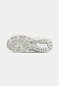 Athletic shoe outsole in gray and white, featuring a textured rubber tread pattern with varying shapes and grooves for traction.