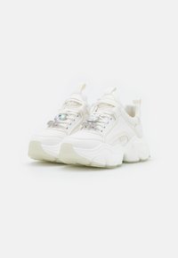 White chunky sneakers with a smooth leather upper, featuring a decorative rhinestone accent and a thick, translucent rubber sole.