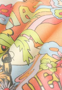 Tejido colorido con un diseño floral y de dibujos animados que presenta vibrantes azules, verdes y naranjas, mostrando una textura suave y una superficie lisa.