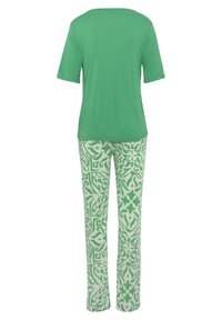 Grünes kurzärmeliges Oberteil mit rundem Ausschnitt, kombiniert mit gemusterten grünen und weißen Hosen, die ein filigranes Design aufweisen.