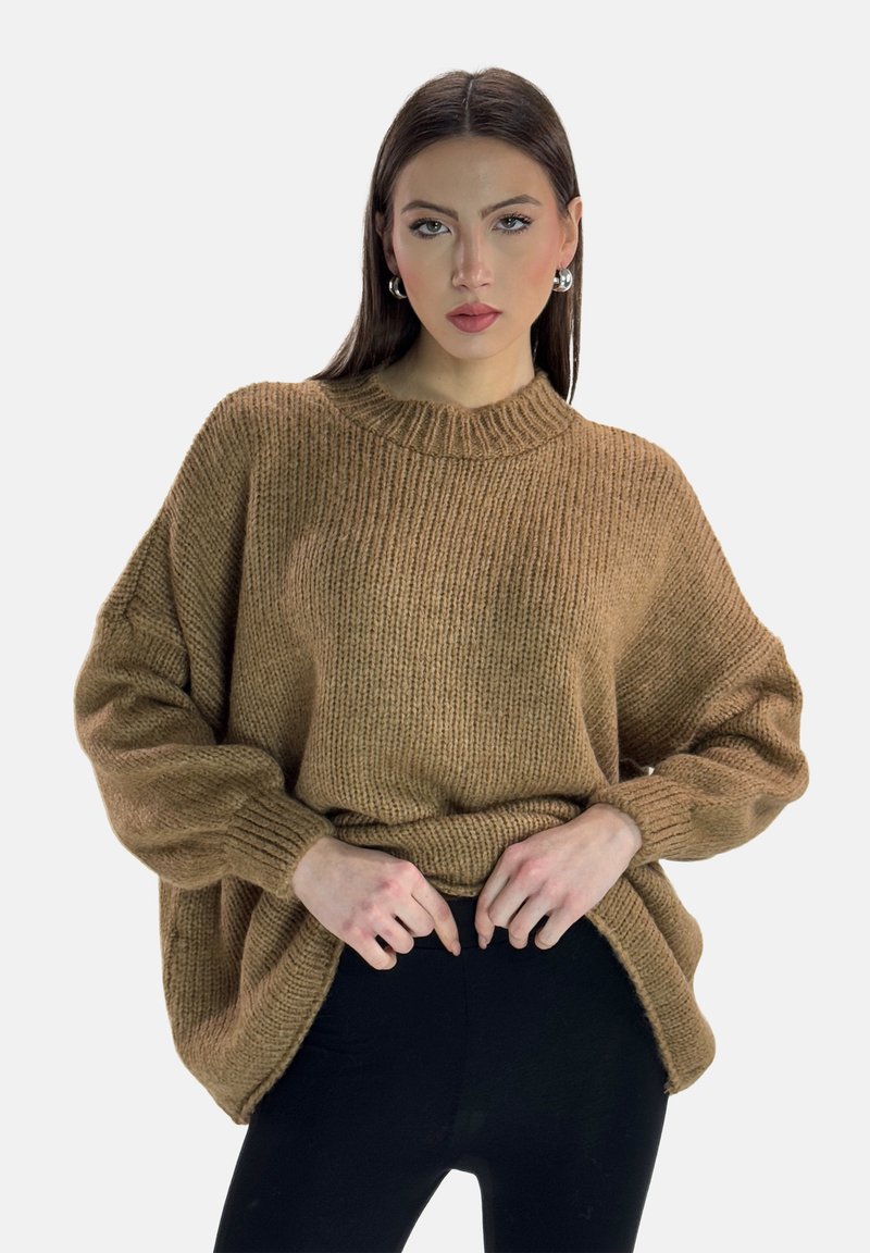 Maglione oversized marrone lavorato a maglia con colletto alto, polsini a coste e spacco laterale, abbinato a leggings neri aderenti.