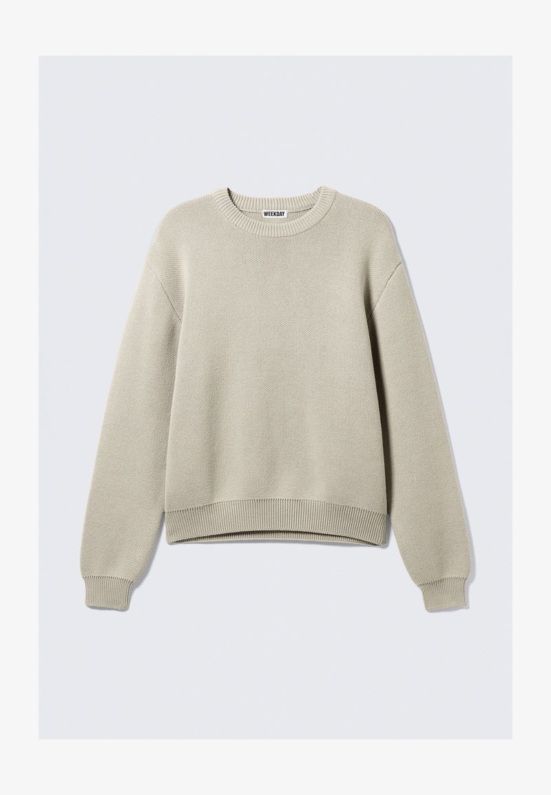Pull en tricot beige avec un col rond, des manches longues et des bords côtes au niveau des poignets et de l'ourlet. Présente un motif texturé sur l'ensemble.