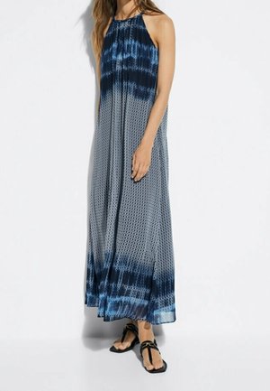Maxi dress featuring a halter neck, blended blue and white geometric patterns, lightweight fabric, and a flowing silhouette.