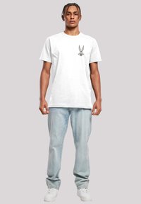 Hvit bomull t-skjorte med korte ermer, med et Bugs Bunny-trykk på brystet. Kombinert med lyseblå jeans og hvite sneakers.