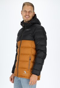 Vadderad jacka med svart överdel och orange underdel, med huva, dragkedjefickor och en logotyp på bröstet. Mjuk textur.