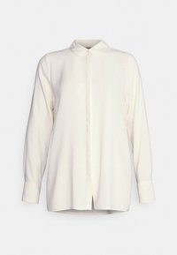 Blusa a maniche lunghe, di un delicato avorio, con apertura frontale a bottoni, colletto classico e vestibilità morbida; tessuto liscio con un leggero lucido.
