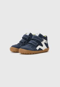 Navy blue high-top shoes with white accents, two velcro straps, rubber sole, and textured fabric uppers. Features stitching details.